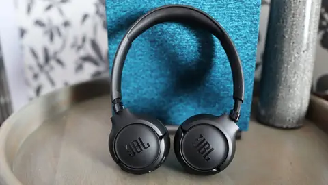 Fone de ouvido JBL Tune preto apoiado sobre uma mesa