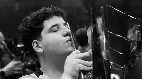 Duduhh, jogador da LOS, beija o troféu do CBLOL em foto em preto e branco