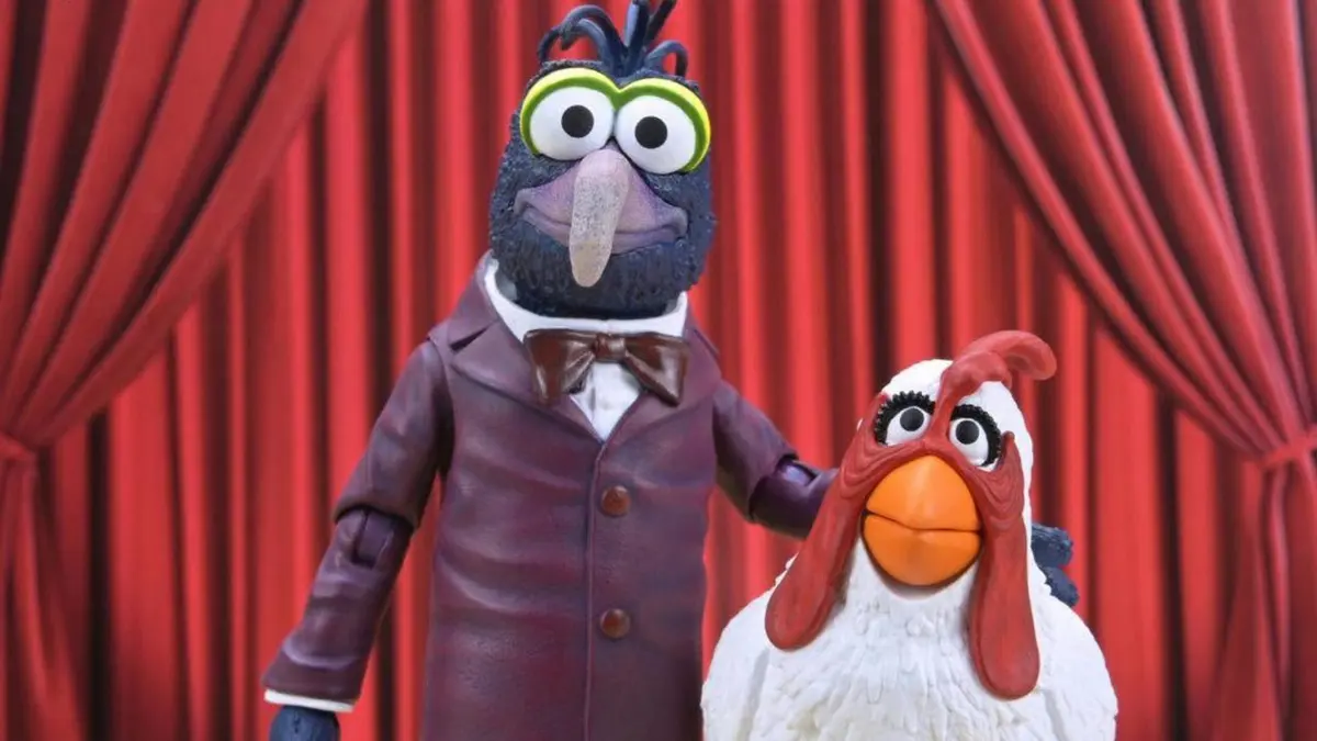 Bonecos articulados Gonzo e Camilla da linha Ultimate dos Muppets diante de cortina vermelha de palco